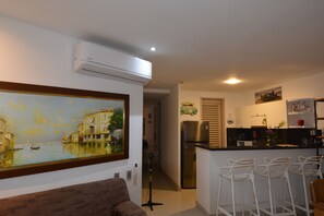 A modern kitchen with a central island, white bar stools, and a painting of a canal scene on the wall. - Oasis Apartment (Cartagena de Indias)