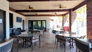 An outdoor patio area with tables and chairs, ceiling fans, and a brick wall. - Spacious 5-bedroom townhome in enchanting Davenport close to Disney (Davenport)