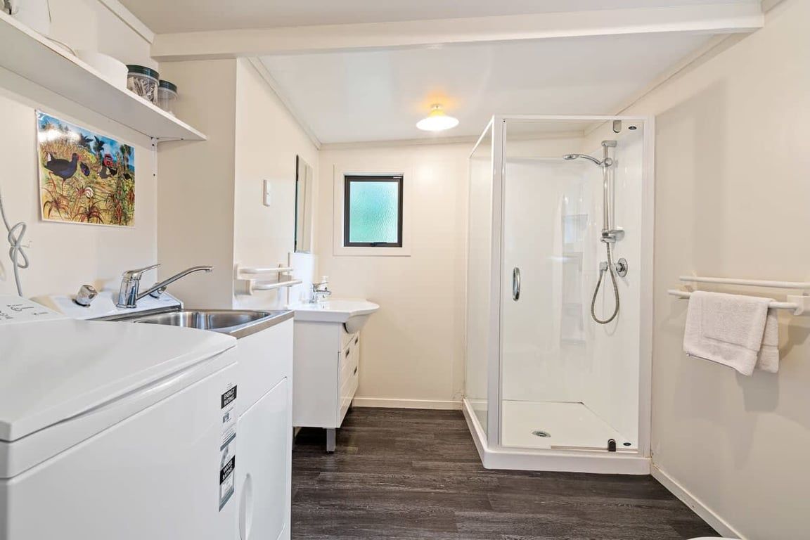 Ein kleines Badezimmer mit Dusche, Waschbecken und Waschmaschine.