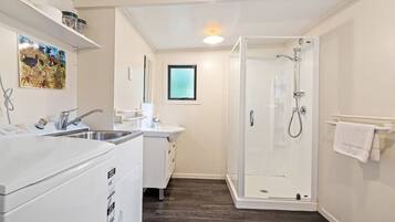 Ein kleines Badezimmer mit Dusche, Waschbecken und Waschmaschine.