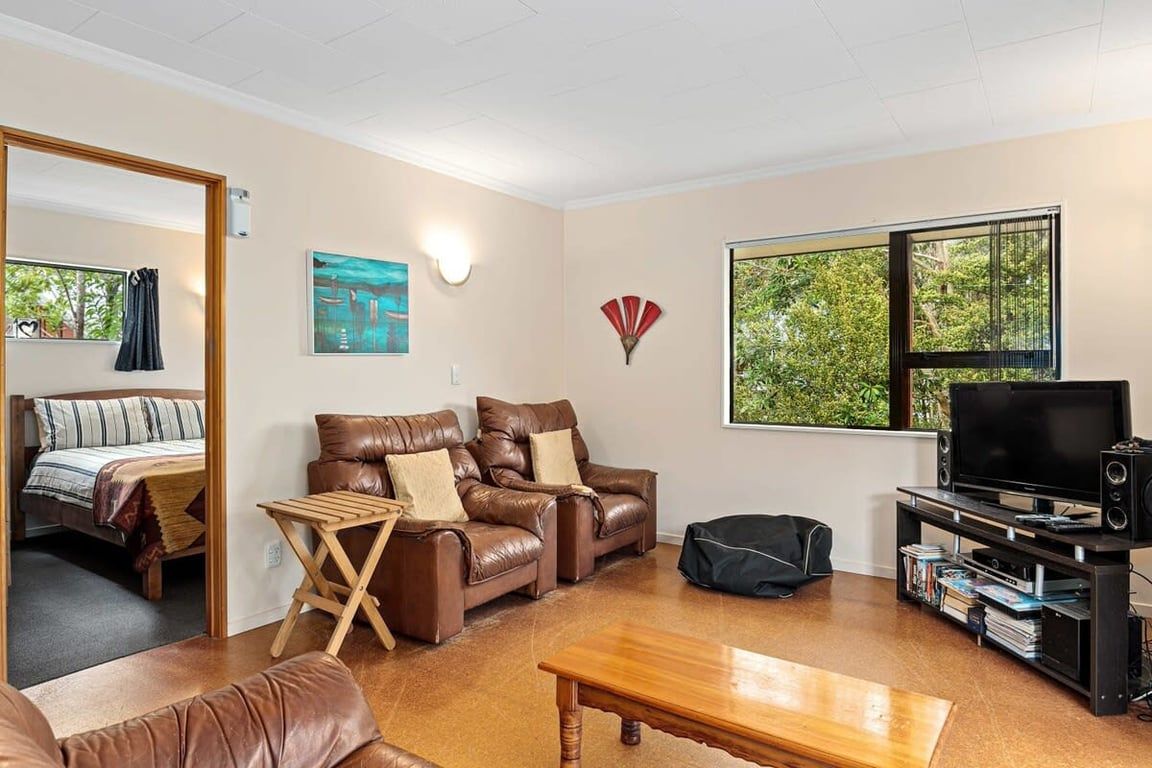 A living room with a sofa, a coffee table, a TV, and a bookshelf.
