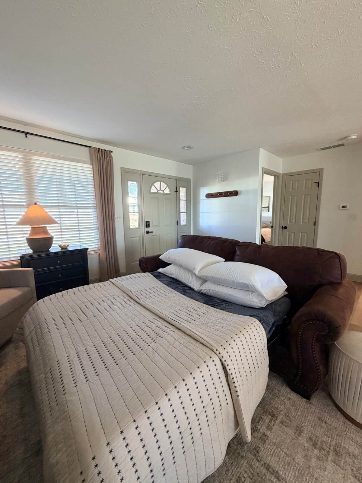 Une chambre à coucher avec un lit, une table de chevet, une lampe, une commode et une porte.