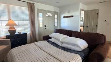 Une chambre à coucher avec un lit, une table de chevet, une lampe, une commode et une porte.