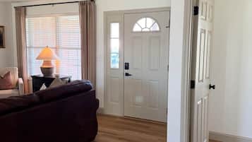 A living room with a sofa, a lamp, and a door leading to another room.