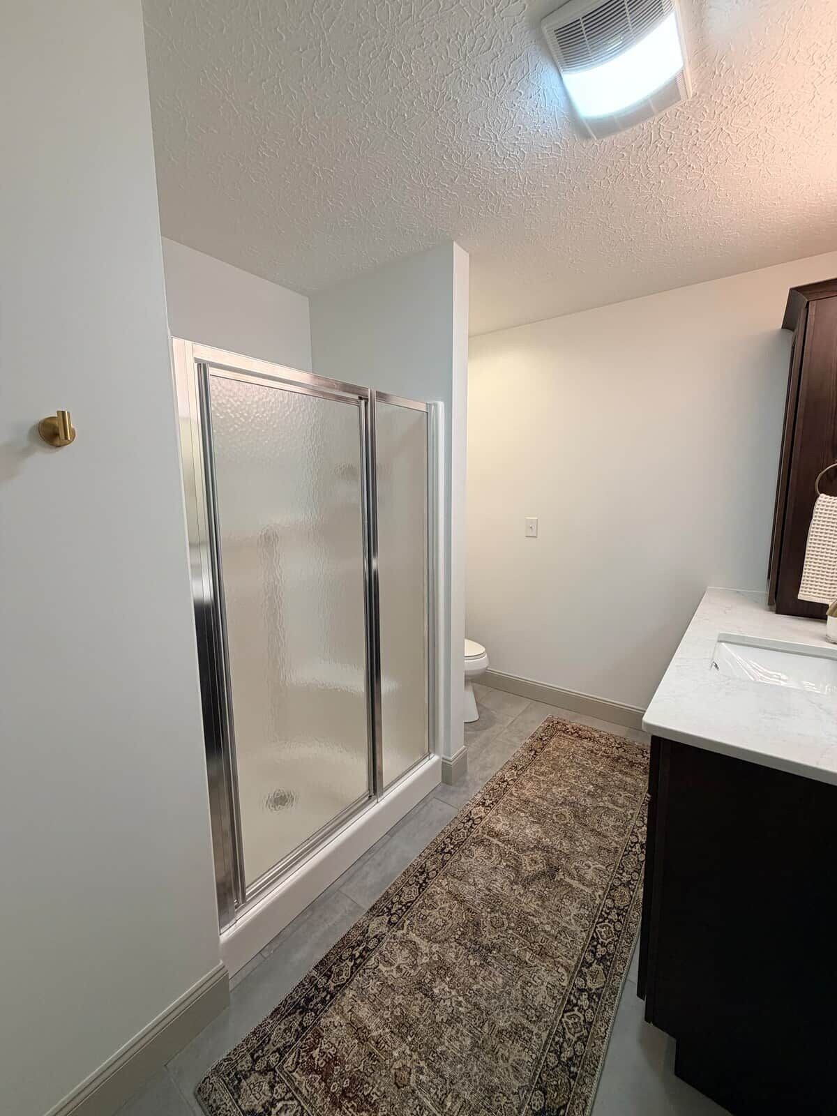 Une salle de bain avec une douche à parois de verre, des toilettes et un lavabo avec un miroir.