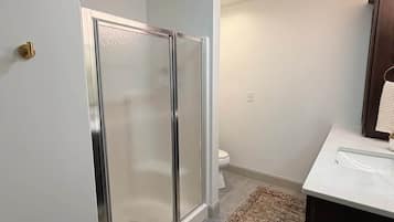Ein Badezimmer mit Duschkabine, Toilette und Waschbecken mit Spiegel.