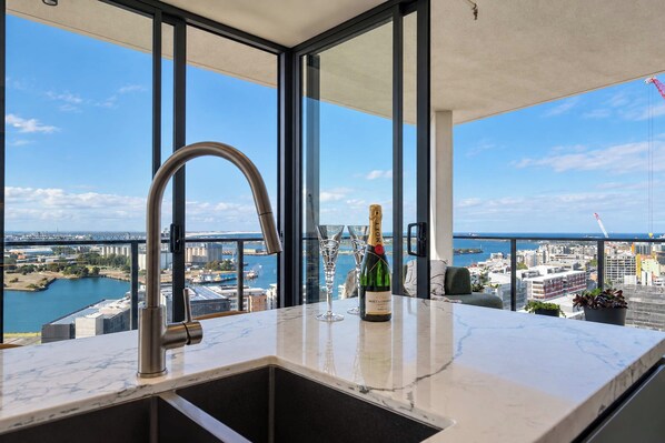 Une cuisine moderne avec une grande fenêtre, un évier et une bouteille de champagne.