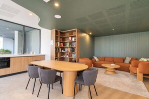 Un intérieur moderne comprenant un coin repas, une bibliothèque et un espace salon avec un canapé et une petite table.