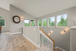 A modern interior with a staircase, large windows, and a decorative wreath. - The Chugach Retreat-Spacious Luxury, Views & Hot Tub, Sleeps 10, FlexibleBooking (Anchorage)