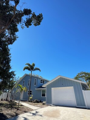 Una propiedad residencial con garaje, un sendero y un árbol pequeño.