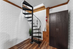 Eine Wendeltreppe mit Metallgestell, Holzboden, einer weißen Ziegelwand und einer dunklen Holztür.