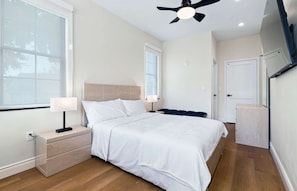 Une chambre d’hôtel équipée d’un lit, de tables de chevet, d’un ventilateur de plafond et d’un téléviseur fixé au mur.