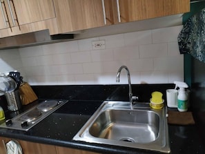 A kitchen with a stainless steel sink, a stove, and a countertop. - MOA Complex 1BR Shore 3 Tower 1 Unit 547 (Pasay)