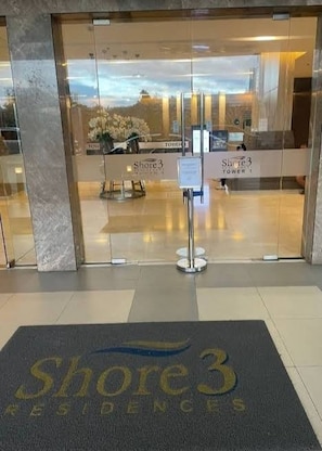 A hotel entrance with a glass door, a reception desk, and a sign reading 'Shore 3 Residences'. - MOA Complex 1BR Shore 3 Tower 1 Unit 547 (Pasay)