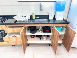 A kitchen with a black countertop, wooden cabinets, and a stainless steel sink. - Duplex Apartment 4 with 2 Suites 450m from the Beach in Santa Cruz Cabrália (Santa Cruz Cabrália)