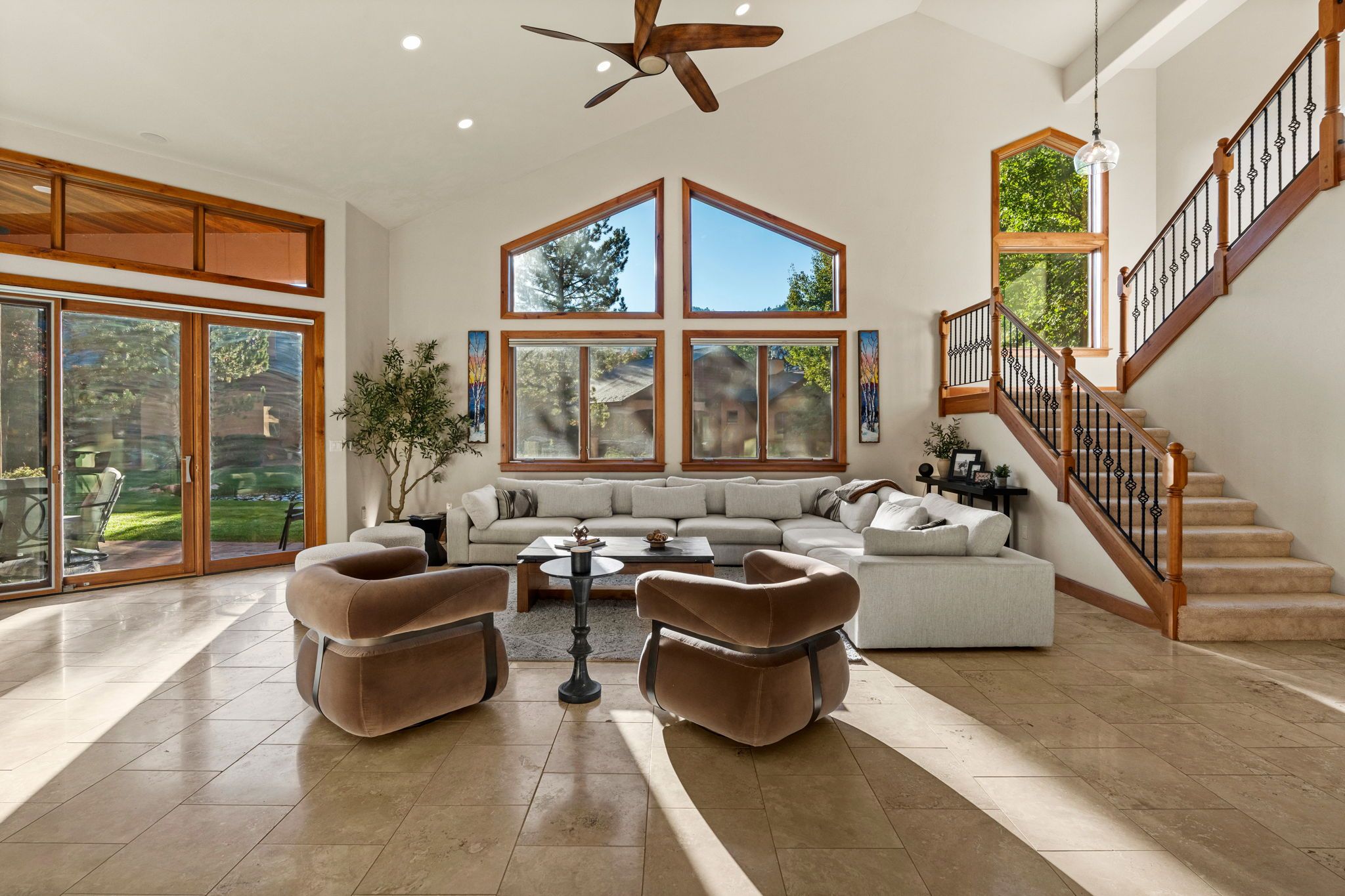 A spacious living room with a large sectional sofa, two armchairs, a coffee table, and a ceiling fan.