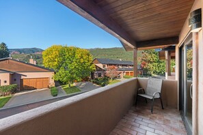 Ein Balkon mit Blick auf ein Wohngebiet, ein Stuhl und eine Holzdecke.