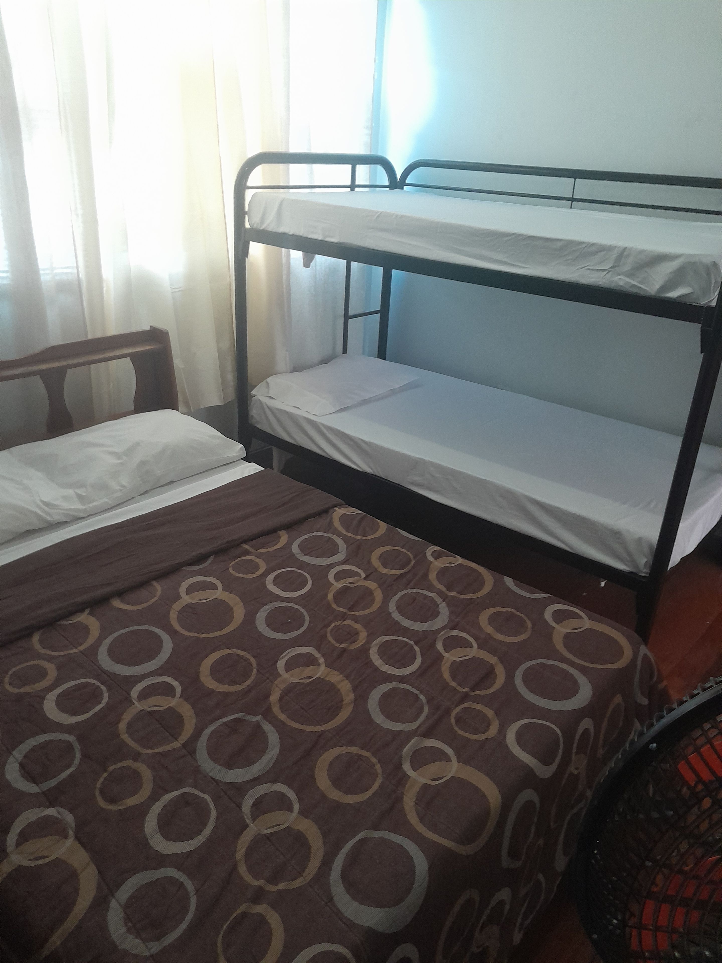 Una cama litera con cabecera de madera, un edredón estampado y una escalera de metal.