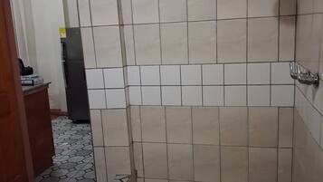 A bathroom with a shower, tiled walls, and a patterned floor.