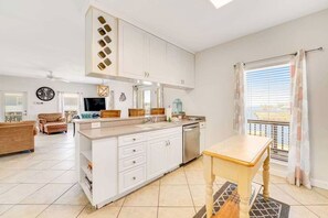Een moderne keuken met witte kasten, een centraal eiland en een eethoek met een tafel.