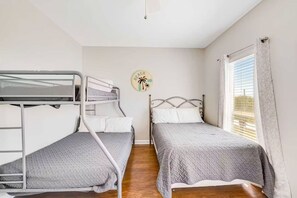A room with two beds, one bunk bed, a wall clock, and a window with curtains. - Family Friendly Home with Private Pool and Dock on the Bay (Gulf Shores)