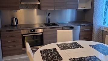 Una cuina moderna amb armaris de fusta, un rentamics d'acer inoxidable i un forn integrat.