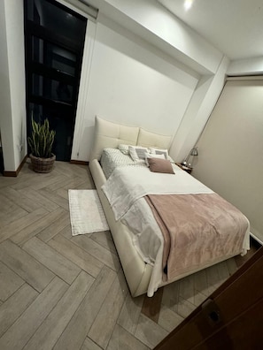 A bedroom with a bed, a potted plant, a nightstand, and a lamp. - Aurea Luxury Apartment Z10 (Guatemala)