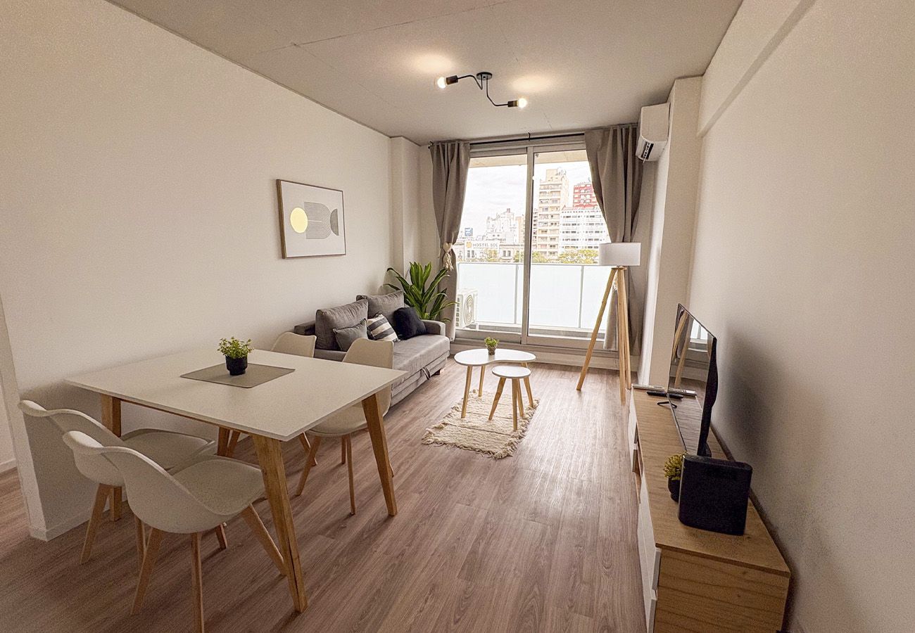 Una sala de estar moderna con comedor, sofá, televisor y vista a la ciudad.