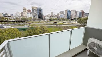 Ein Balkon mit Blick auf die Stadt, einem weißen Geländer und einem Standventilator.