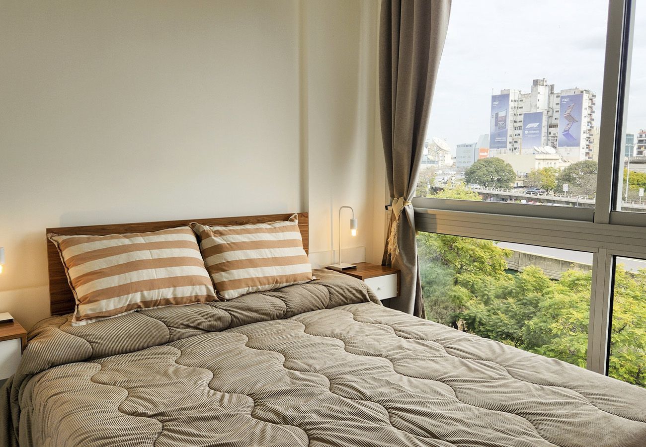 Una cama con almohadas a rayas, una colcha acolchada y una mesita de noche con una lámpara.