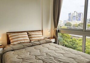 Una cama con almohadas a rayas, una colcha acolchada y una mesita de noche con una lámpara.