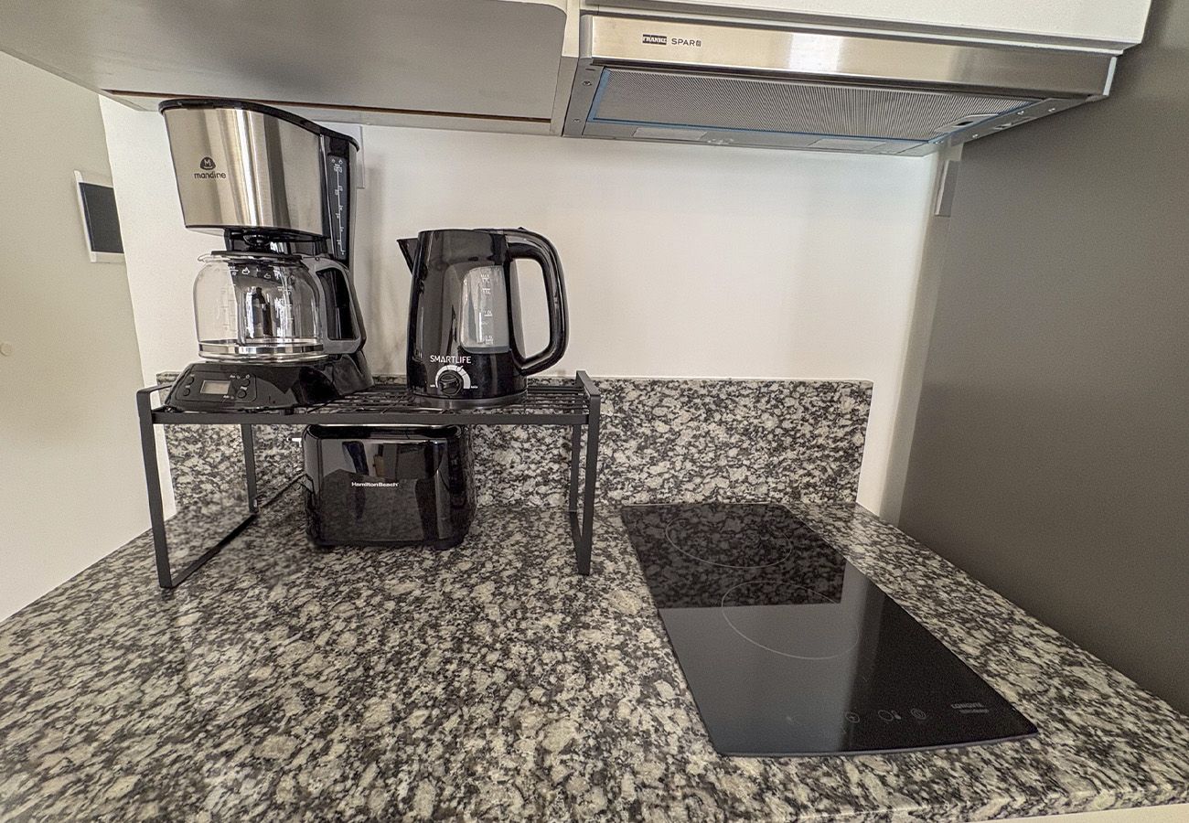 Eine Küchenzeile mit Kaffeemaschine, Wasserkocher und einer kleinen Arbeitsfläche.
