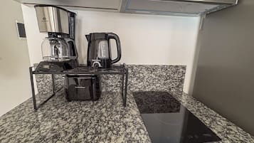 Eine Küchenzeile mit Kaffeemaschine, Wasserkocher und einer kleinen Arbeitsfläche.