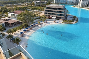 Ein Resort mit großem Schwimmbad, Liegestühlen und Palmen.