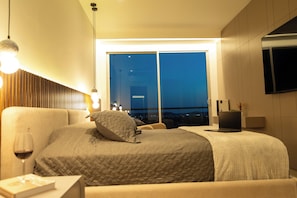Ein modernes Hotelzimmer mit einem großen Bett, einem Schreibtisch und einem an der Wand befestigten Fernseher.