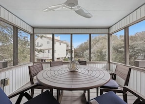 A covered patio with a round table and chairs, a ceiling fan, and a view of houses and trees. - Welcome to your ultimate coastal escape! 2min walk to a private beach (Kitty Hawk)