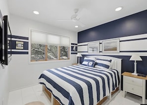 A bedroom with a bed, a nightstand, a ceiling fan, and a window with blinds. - Welcome to your ultimate coastal escape! 2min walk to a private beach (Kitty Hawk)