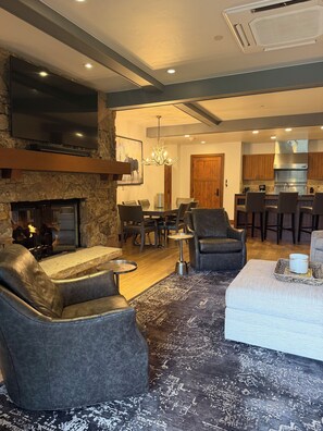 A modern living room with a fireplace, leather sofas, a dining area, and a kitchen. - Snow Cloud Slope Side Dream
3 bedroom/3 1/2 bath ski in/ski out (Avon)