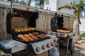 Ein Grill mit verschiedenen Zubereitungsoptionen, darunter ein Seitenbrenner und Gasanschluss.
