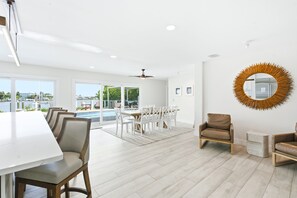 A spacious room with a dining area, a pool view, and a ceiling fan. - The Beach Life - 4 BR 2.5 BA  premier home w/ pool & waterview (Indian Rocks Beach)