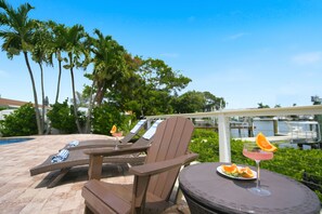 A poolside area with lounge chairs and a table with a drink. - The Beach Life - 4 BR 2.5 BA  premier home w/ pool & waterview (Indian Rocks Beach)