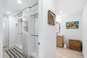 Un baño moderno con cabina de ducha, un adorno de pared de madera, un cuadro enmarcado de caballito de mar y una pequeña cesta de mimbre.