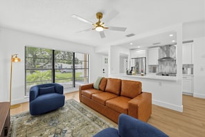 A modern living room with a brown leather sofa, a blue armchair, and a patterned rug. - Central Tampa Oasis : Near Stadium, Downtown & TPA (Tampa)