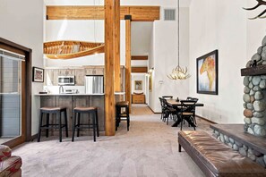 Un intérieur moderne comprenant une cuisine, un coin repas et une cheminée en pierre.