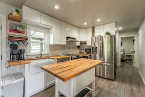 A modern kitchen with white cabinetry, a wooden countertop, stainless steel appliances, and a window with a view. - Discover your new favorite hideaway, Casitas By The Sea (Fort Bragg)