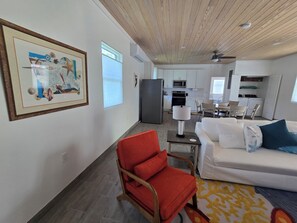 Una sala de estar moderna con una silla roja, un sofá blanco y un comedor con mesa y sillas.