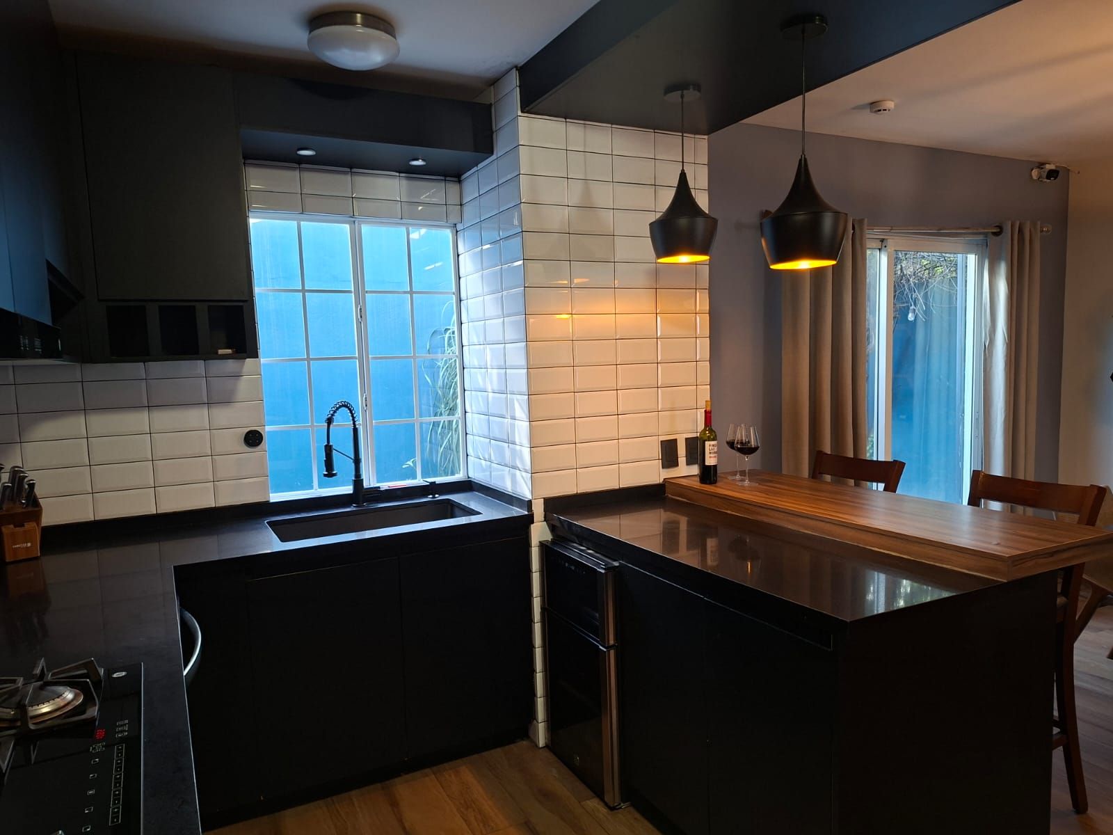 Una cocina moderna con una isla central, un lavamanos integrado e iluminación colgante.
