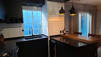 Una cocina moderna con una isla central, un lavamanos integrado e iluminación colgante.