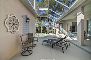 Ein überdachter Außenbereich mit Pool, Liegestühlen und einer Pergola.