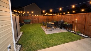 A backyard with artificial lighting, a wooden fence, and outdoor furniture. -     Luxury 2BR Summerville Retreat / Modern, Cozy & Close to Everything (Summerville)